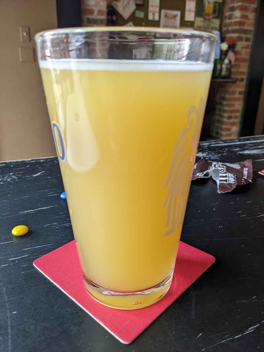 A hazy pale ale on a red coaster, on the dark bar top at Gumbo Bottoms